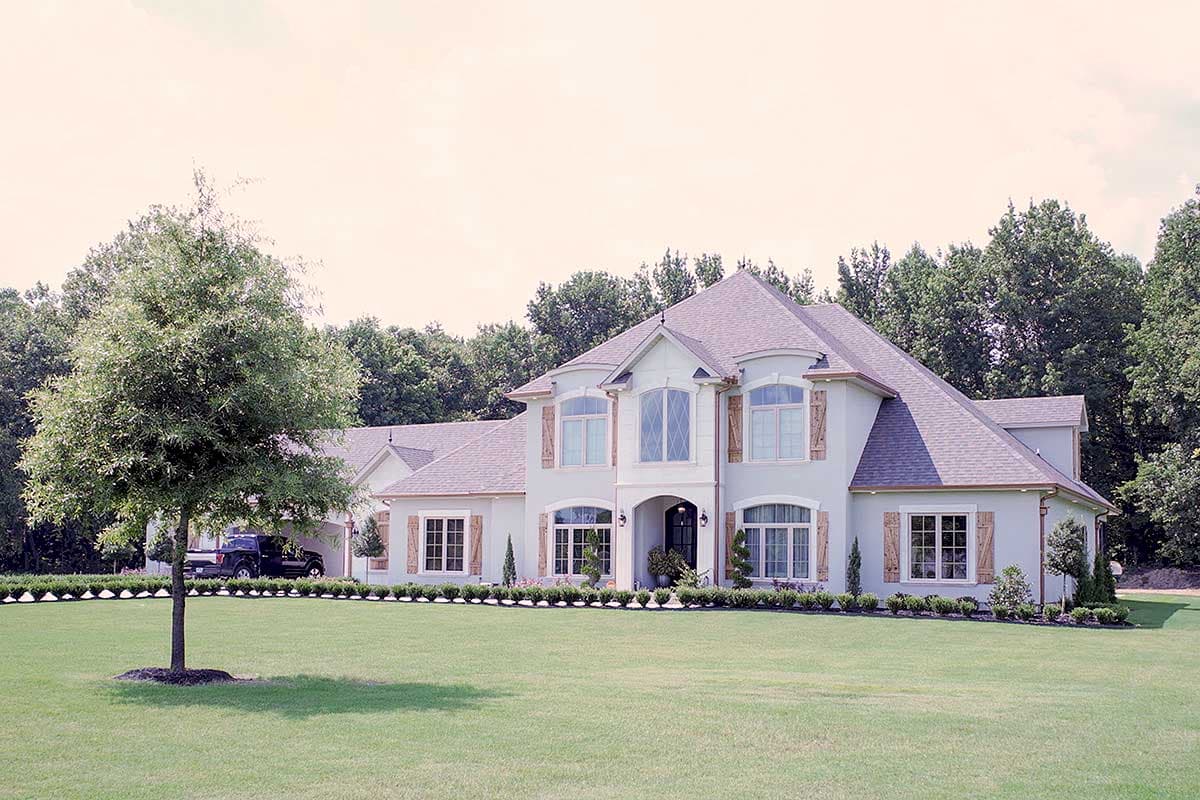 House plan exterior featuring a two-story design with arched windows, multiple gables, and a side-entry garage.