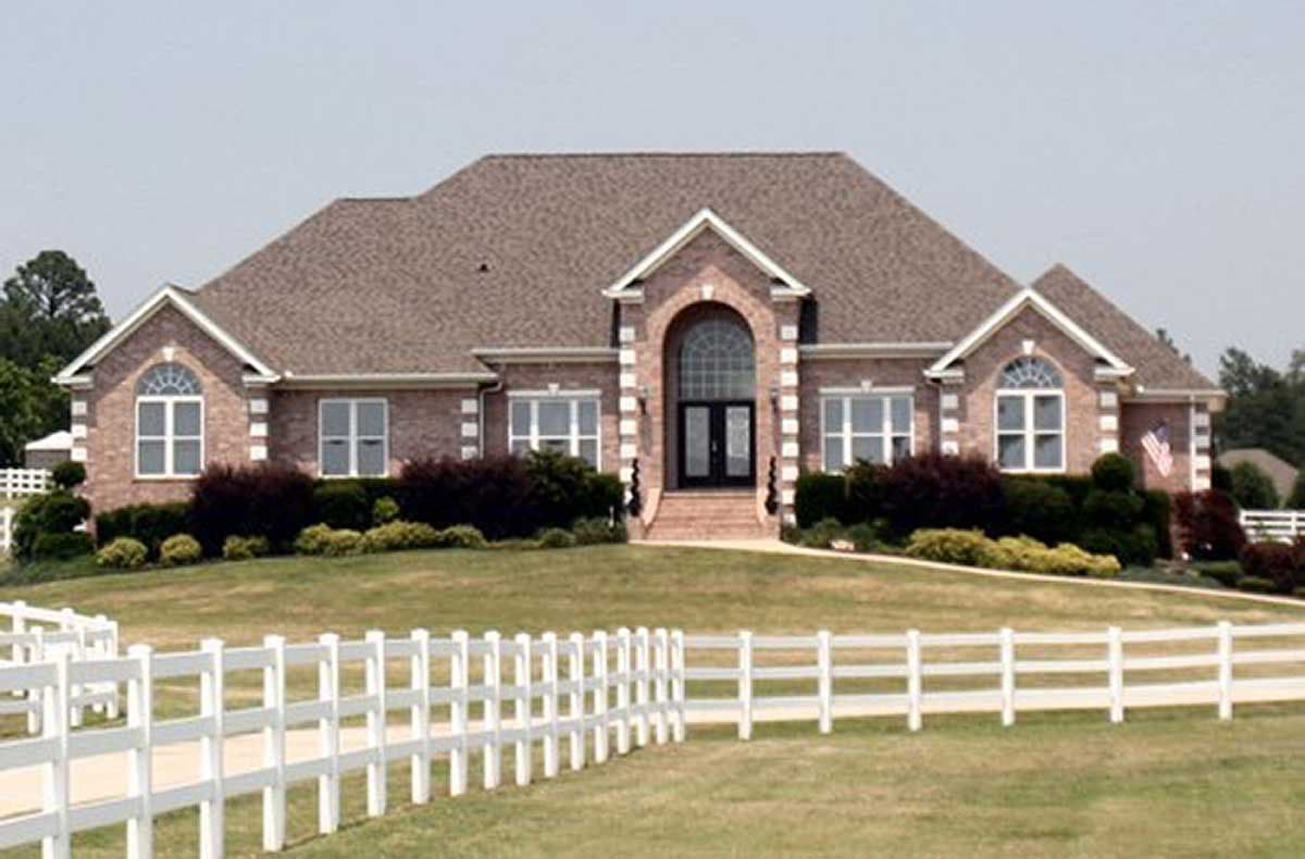 House plan exterior: Two-story brick home with arched entryway, symmetrical gables, and multi-pane windows.