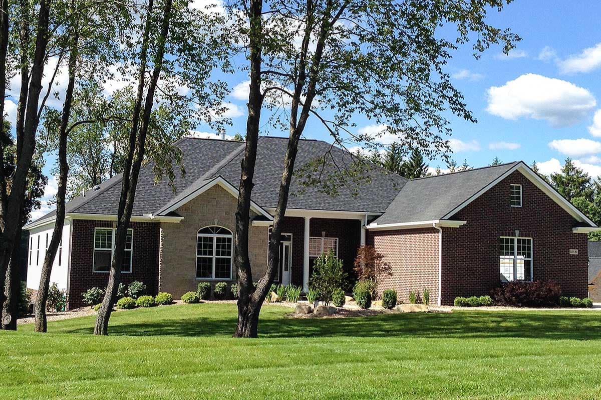 House plan exterior: Ranch-style home with brick and stone facade, prominent gables, and covered entry.