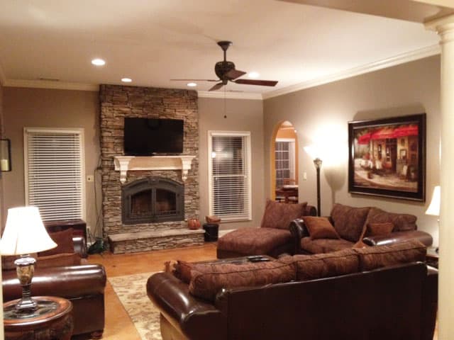 Living room with stacked stone fireplace, built-in TV, arched doorway, and plush seating.