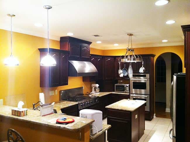 Kitchen with dark wood cabinets, granite countertops, stainless steel appliances, center island, and a breakfast bar.