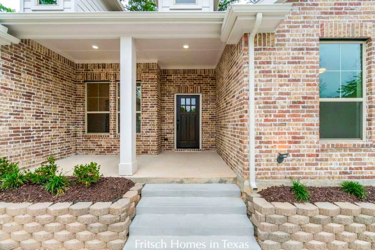 House plan exterior: brick facade, covered porch with white columns, gable roofline, and multi-pane front door.