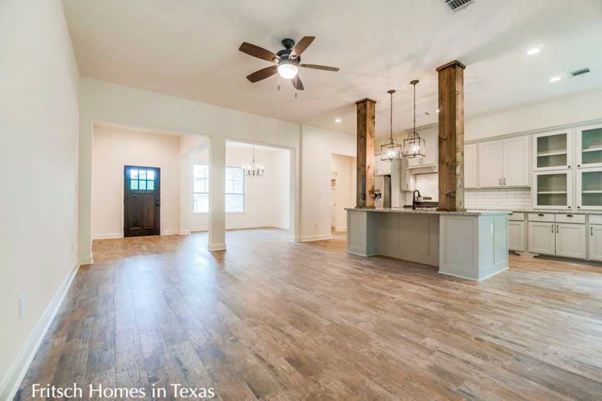 Open concept interior with view of entryway, dining area, and kitchen island with pendant lighting and wood beam supports.