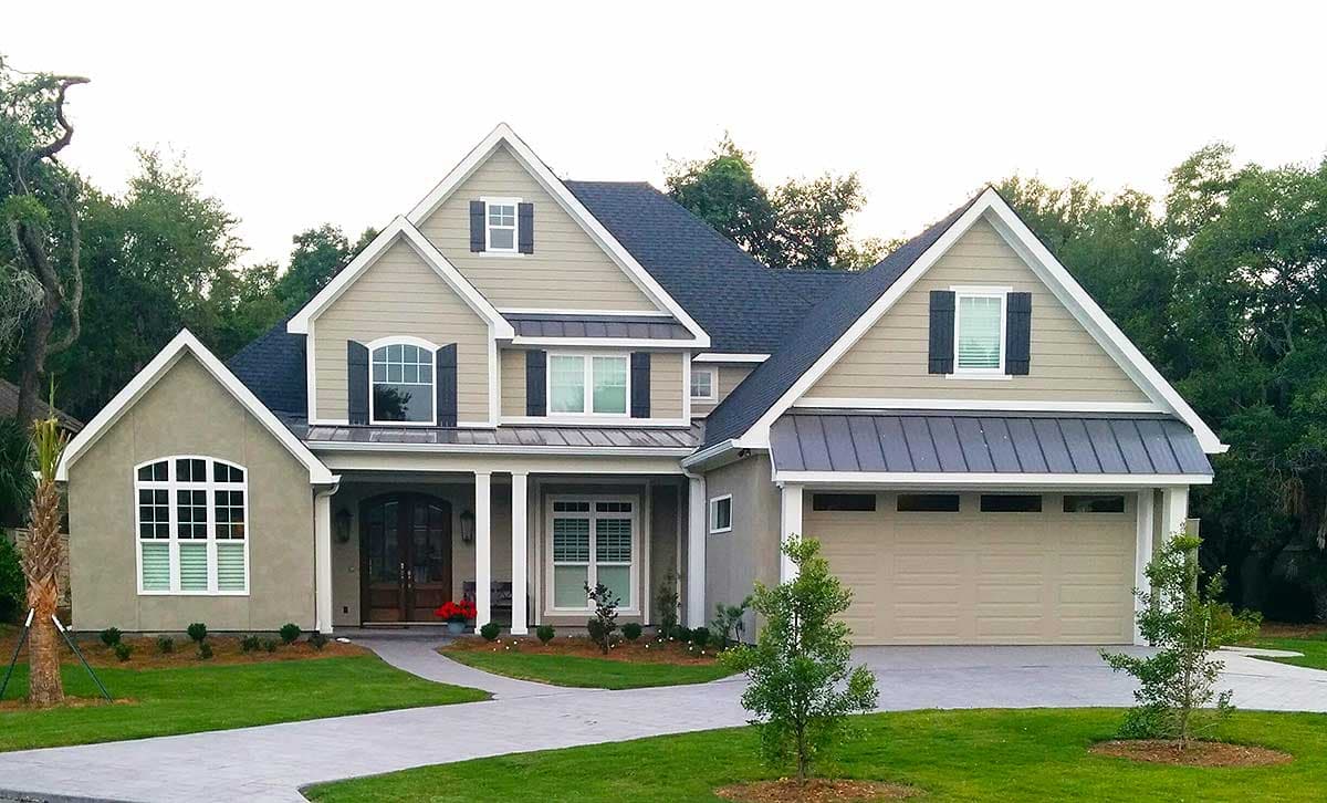 House plan exterior: Two-story home with gables, front porch with columns, metal roof accents, and a side-facing garage.
