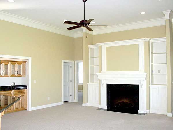 Interior view of a living room with a fireplace, built-in shelving, a wet bar, and a ceiling fan.