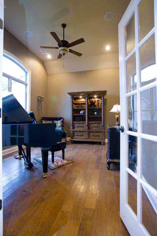Interior view of a room with a grand piano, built-in shelving unit, and glass-paned doors.