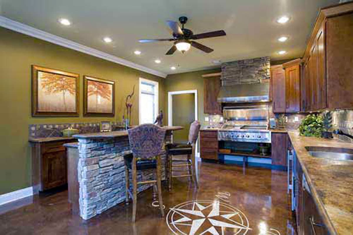 Kitchen with stone island, stainless steel range, wood cabinets, and decorative floor compass.