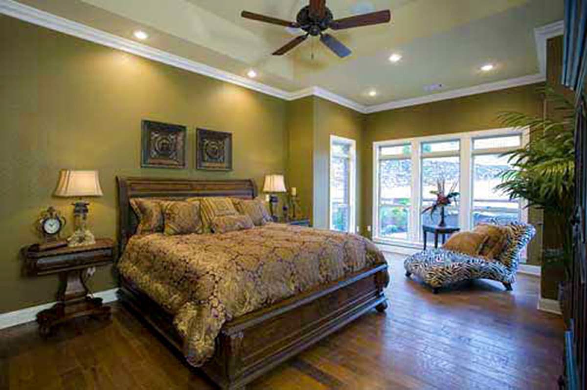 Bedroom with large bed, ceiling fan, recessed lighting, and windows. Includes a chaise lounge and bedside tables.