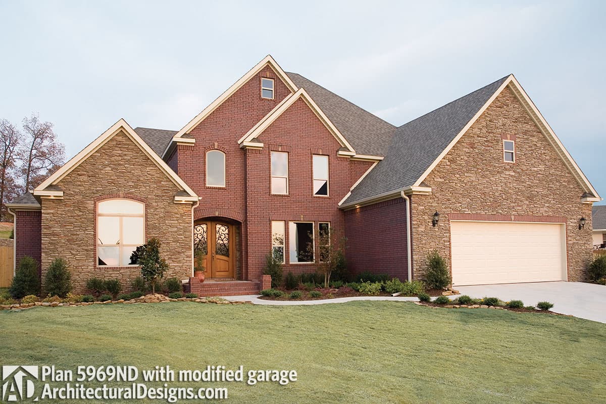 House plan exterior with brick and stone facade, arched entry, multiple gables, and a side-entry garage.