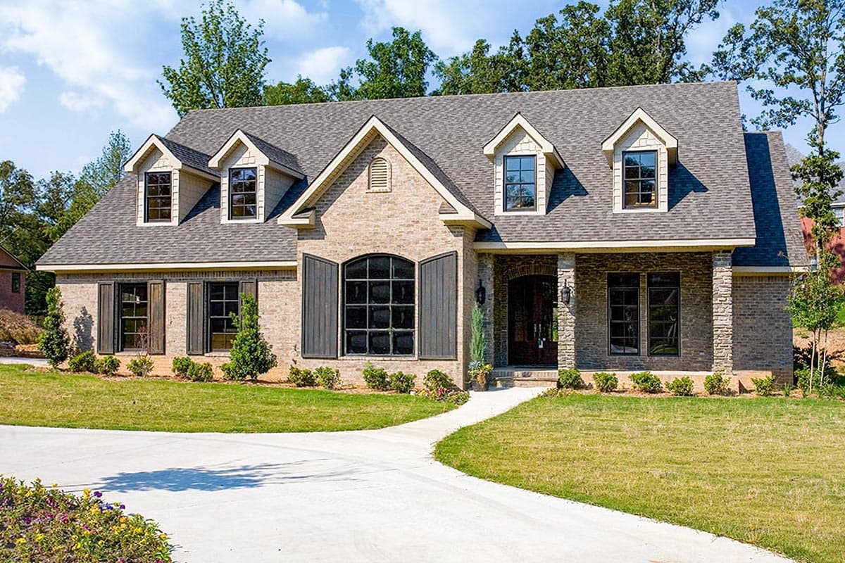 House plan exterior with brick facade, multi-gabled roof, three dormers, and shuttered windows. Includes arched window over front entry.