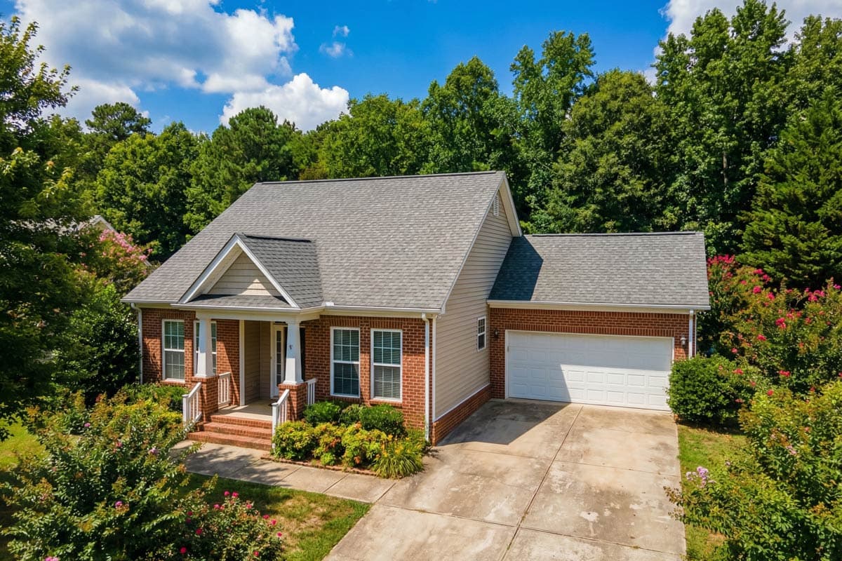 House plan exterior: Gable roof, brick and siding, covered front porch, and attached two-car garage.