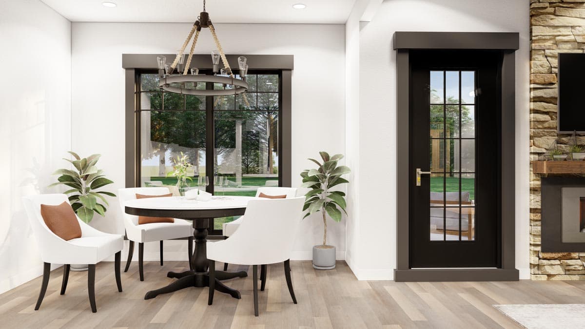 Dining area with white chairs, dark pedestal table, large window, and black door with glass panes. House plan interior.