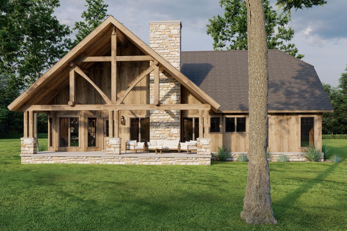Log home exterior with prominent timber framing, stone chimney, and covered porch. Rustic, two-story design.