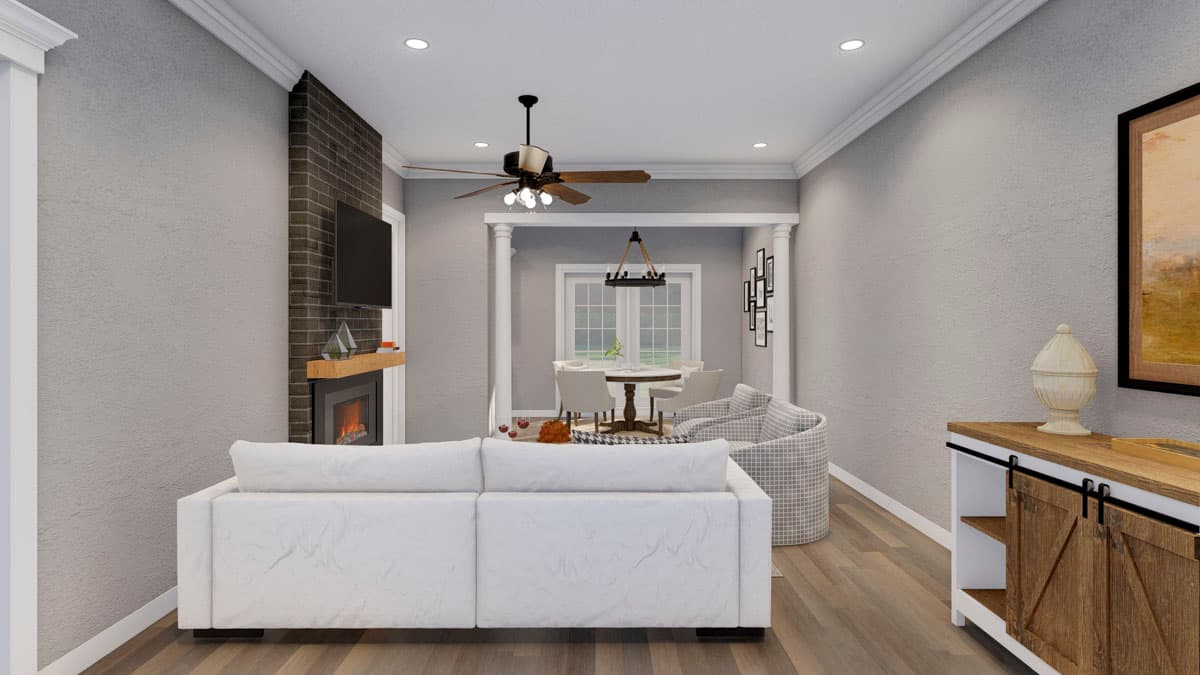 Living room with fireplace, media console, and dining area beyond. Open layout with white sofa and patterned chair.