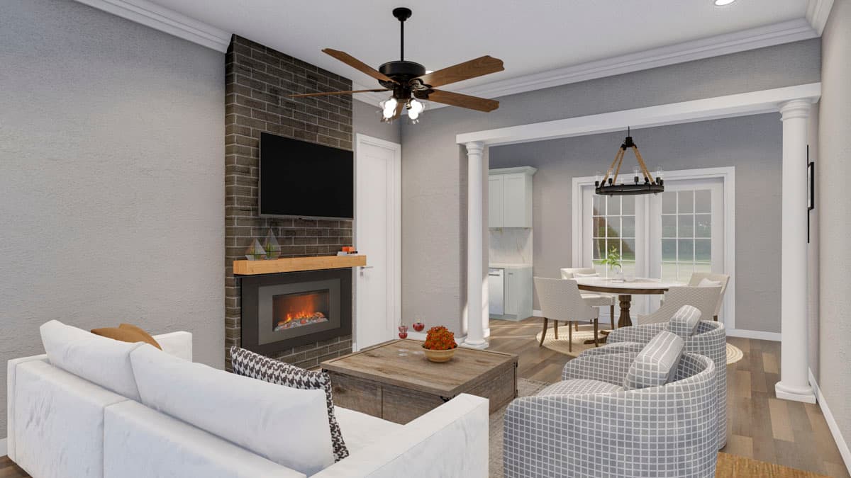Living room with brick fireplace, TV, ceiling fan, seating area, and dining area beyond with chandelier.