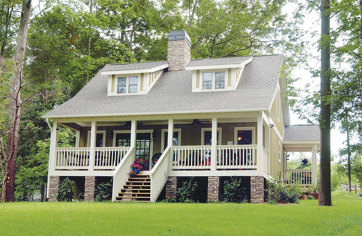 House plan exterior: Craftsman style, two-story with prominent stone foundation, wraparound porch, and two front dormers.