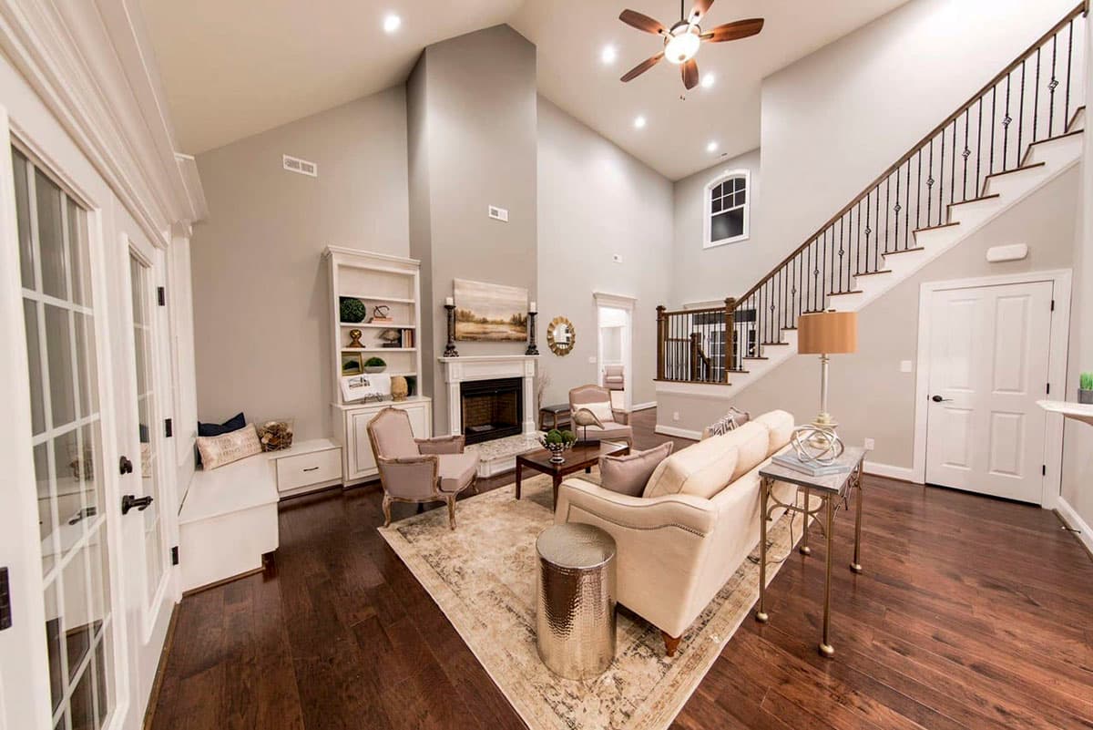 Interior rendering: Great room with vaulted ceiling, fireplace, built-in bookshelves, and staircase.