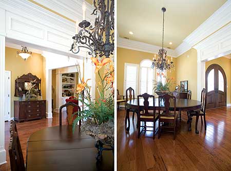 Interior view of a dining room with a round table and chairs, ornate chandelier, and arched double doors.