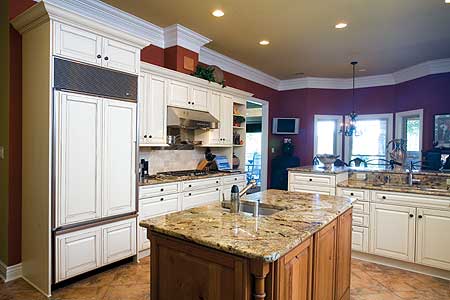 Kitchen with white cabinets, granite island, stainless steel appliances, and a double oven range.