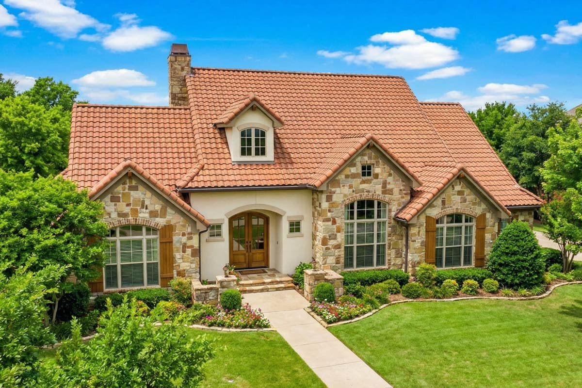 House plan exterior: Mediterranean style, two stories, red tile roof, stone accents, arched entryway, prominent gables, and dormer window.