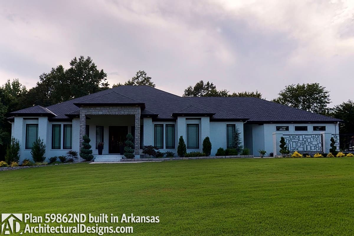 House plan exterior: One-story modern home with stone-accented entrance, symmetrical windows, and decorative metal screen.