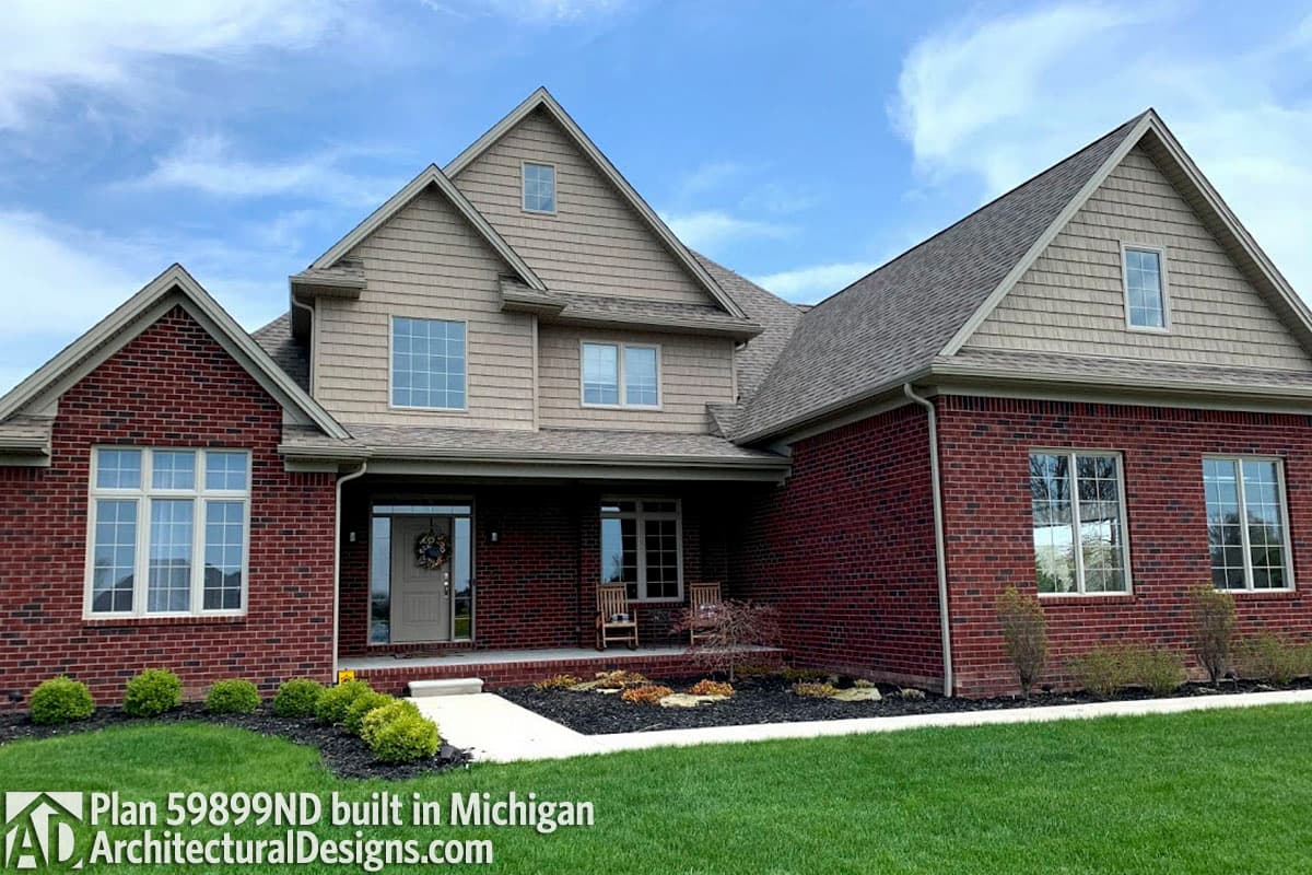House plan exterior: Two-story home with brick facade, prominent gables, and shingle siding.
