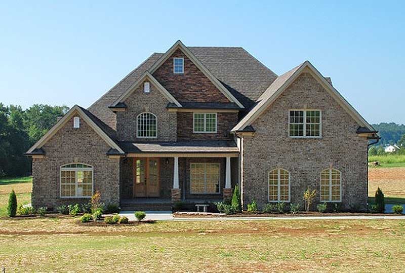 House plan exterior with brick facade, prominent gables, arched windows, and covered front porch.