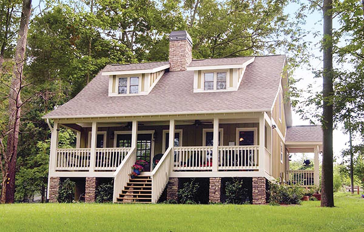 House plan exterior: Two-story home with wraparound porch, stone foundation, and dormer windows.