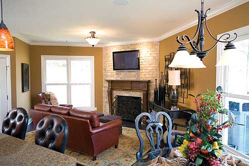 Living room interior with fireplace, leather sofa, dining chairs, and chandelier.