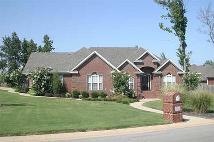 House plan exterior: One-story brick home with gabled rooflines, arched entry, and prominent front walk.