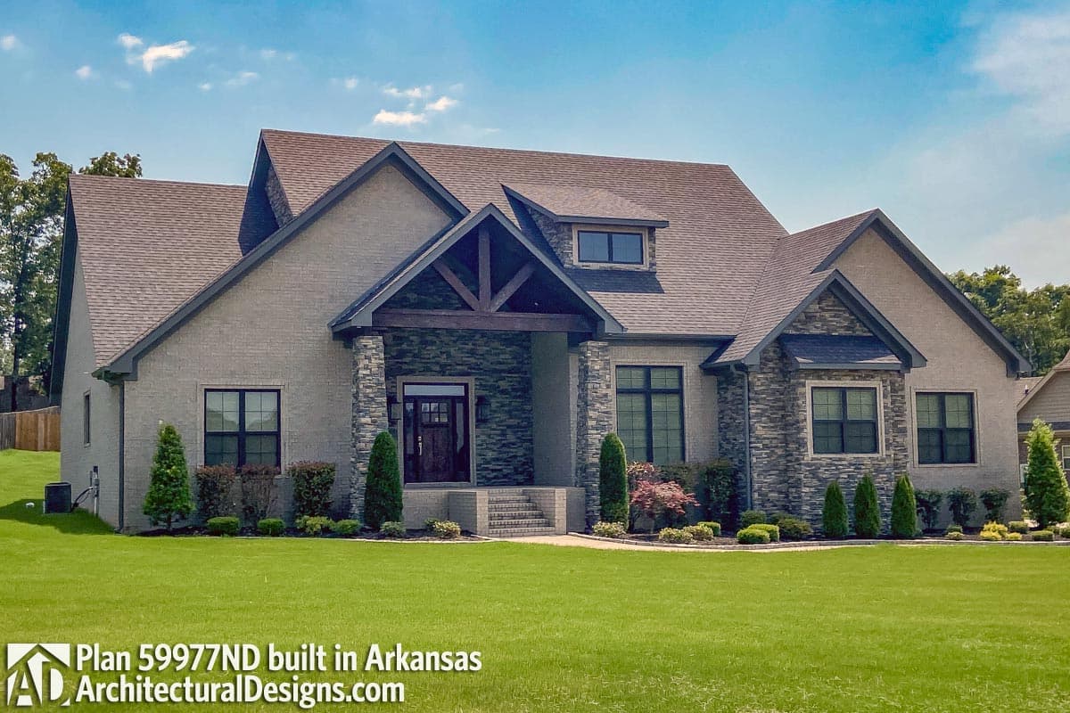 House plan exterior with stone accents, covered entryway with exposed beams, and multiple gables.