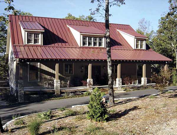 House plan exterior: Two-story home with metal roof, dormers, wraparound porch supported by stone and wood columns.