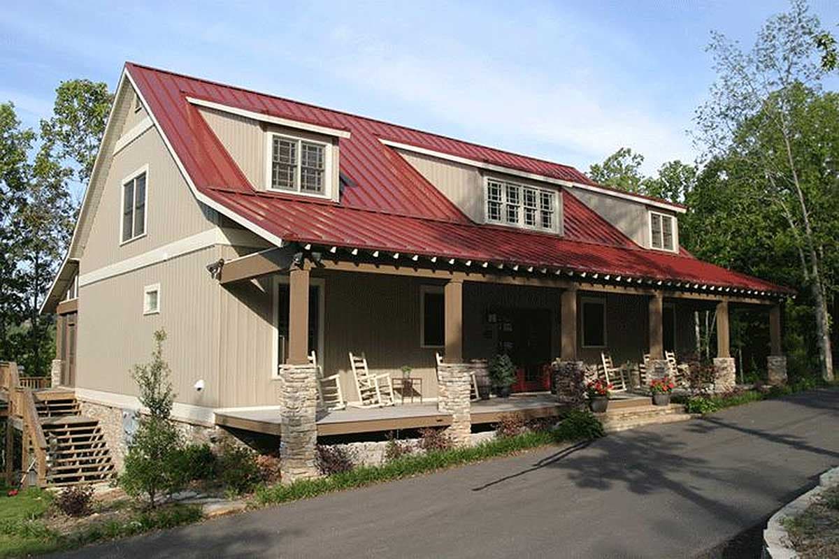 House plan exterior: Two-story Modern Farmhouse with red metal roof, dormers, and wrap-around porch supported by stone and wood columns.
