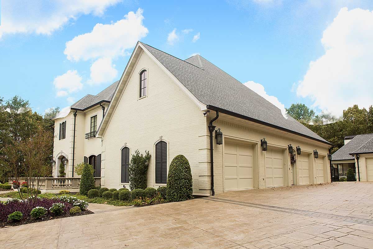 House plan exterior: White brick two-story home with a five-car garage, gabled dormer, and arched windows.