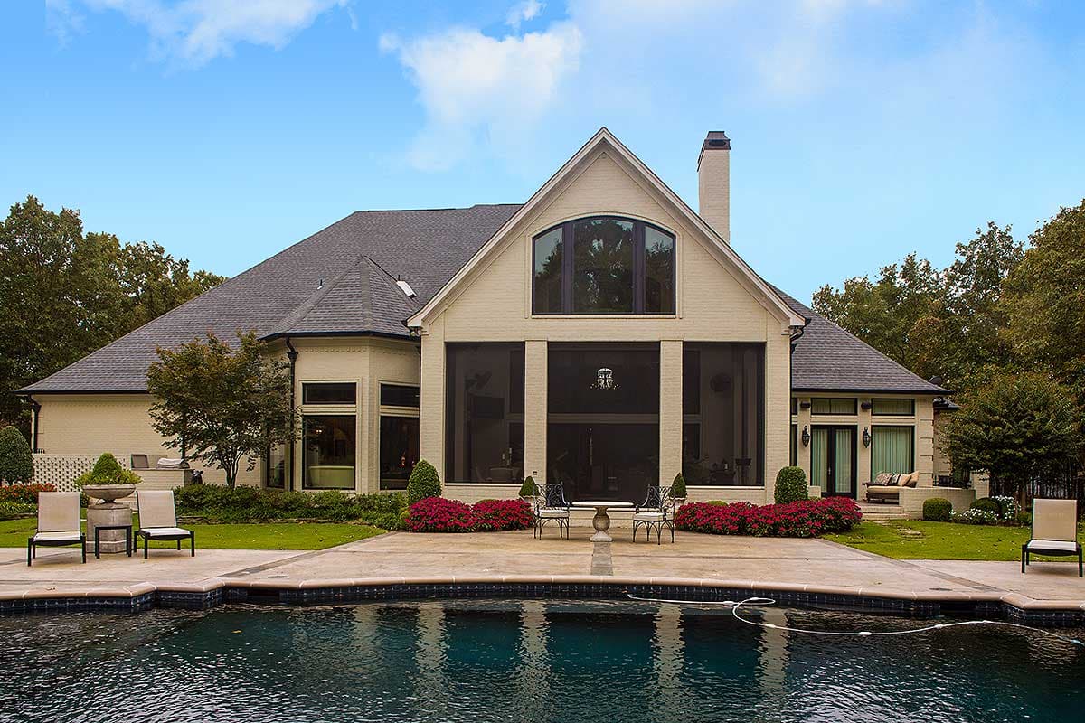 House plan exterior: Two-story brick home with a steeply pitched roof, large central gabled section, and multiple arched windows.