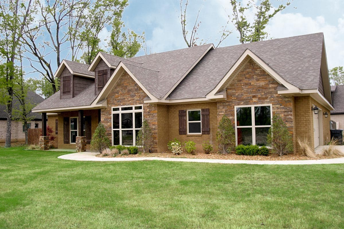House plan exterior: One-story ranch with stone and brick facade, multiple gables, dormers, and covered entry.