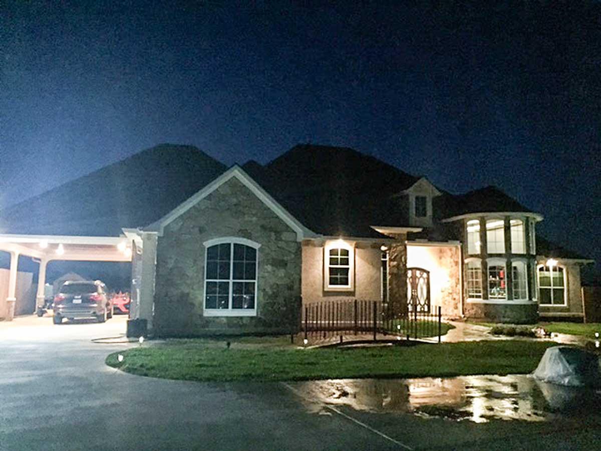 House plan exterior, two stories, stone accents, arched window, dormer, and covered carport.