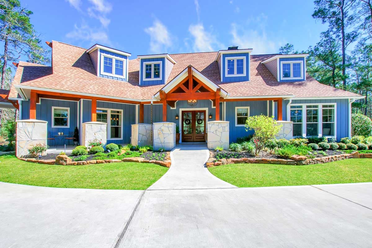 House plan exterior: Craftsman style, 1.5 stories, large gabled entrance, dormers, stone accents, and a covered porch.