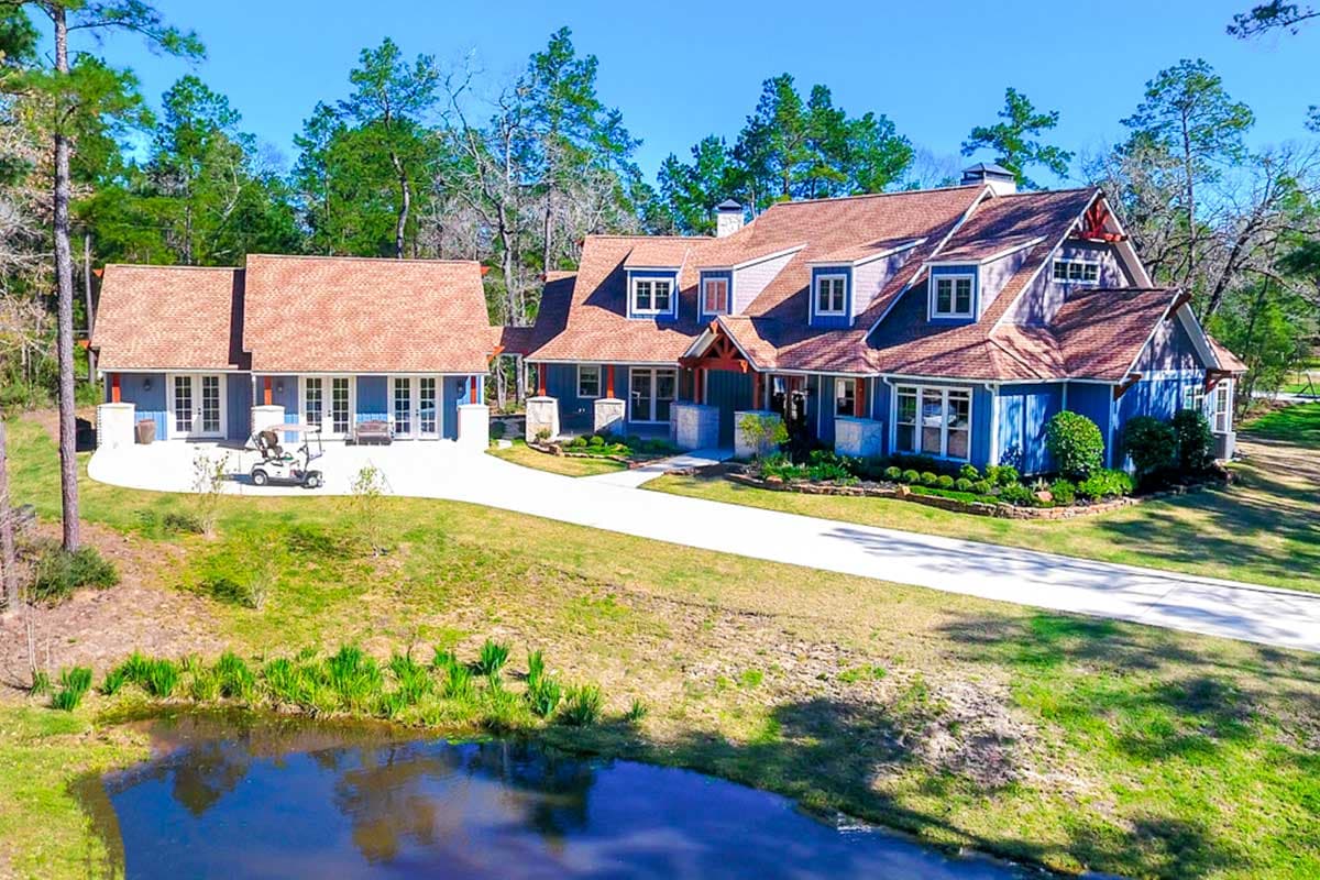 House plan exterior. Two-story home with multiple gables, dormers, and a detached garage with similar roofing. Blue siding with red accents.