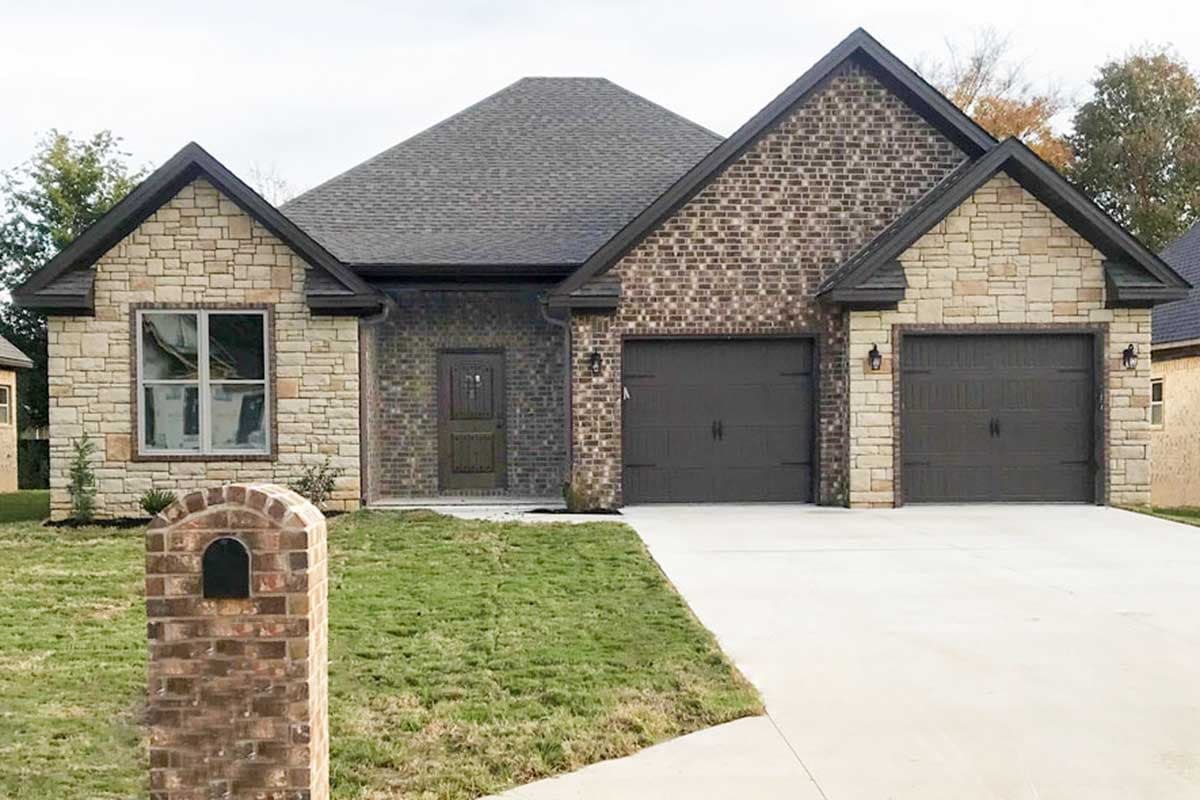 House plan exterior: one-story home with stone and brick facade, gable rooflines, and a double garage.