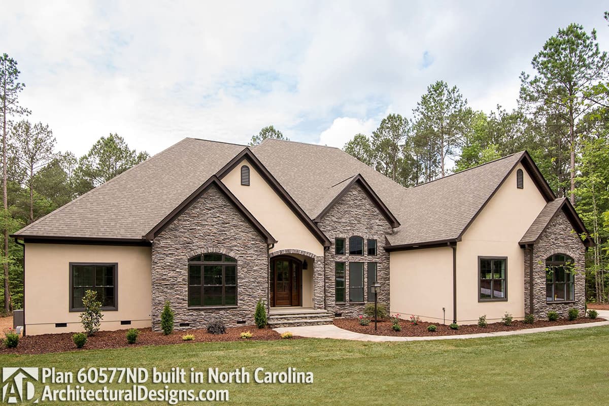 House plan exterior: One-story home with stone accents, arched windows, and a covered entry with a wood door.