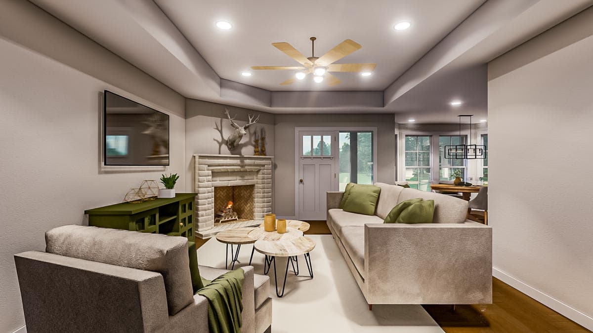 Cozy living room interior featuring a fireplace, a mounted TV, a beige sofa with green pillows, and light wooden ceiling fan.