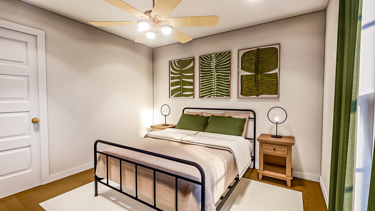 A bedroom with a metal bed frame, two nightstands, and three botanical art prints on the wall. A ceiling fan and green curtains add to the decor.