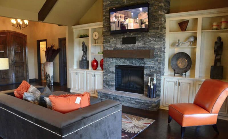 Living room with stone fireplace, built-in shelving, and sectional sofa.
