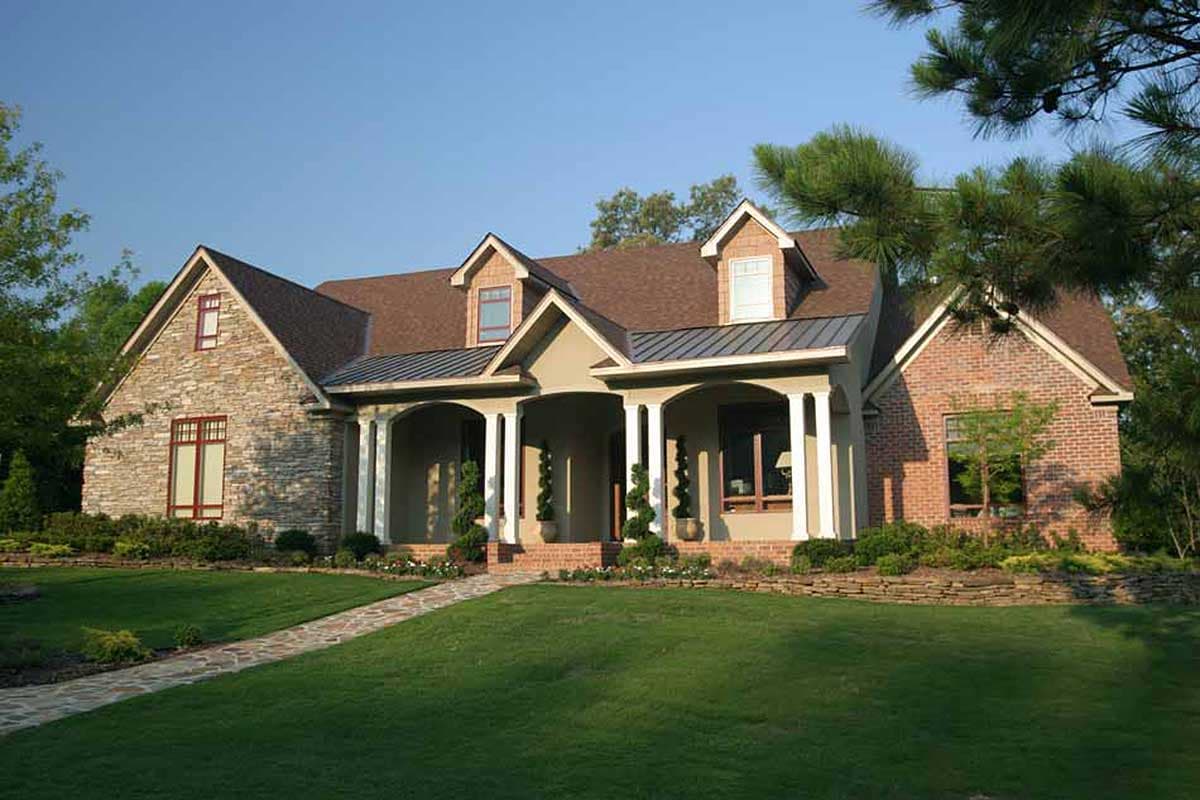House plan exterior: Two-story home with stone and brick facade, covered porch with columns, and dormers.