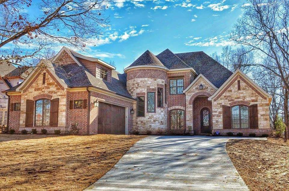 Two-story house plan exterior with brick and stone facade, gabled dormers, arched entryway, and a turret.