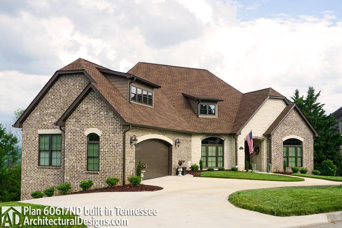 House plan exterior: Two-story brick home with a side-entry garage, prominent gables, and dormer windows.