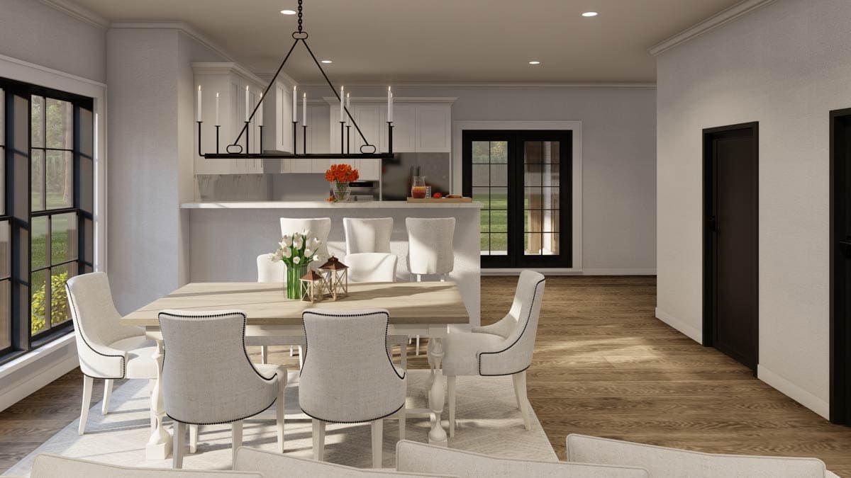 Dining room with chandelier, island seating, and French doors leading outside. House plan rendering.