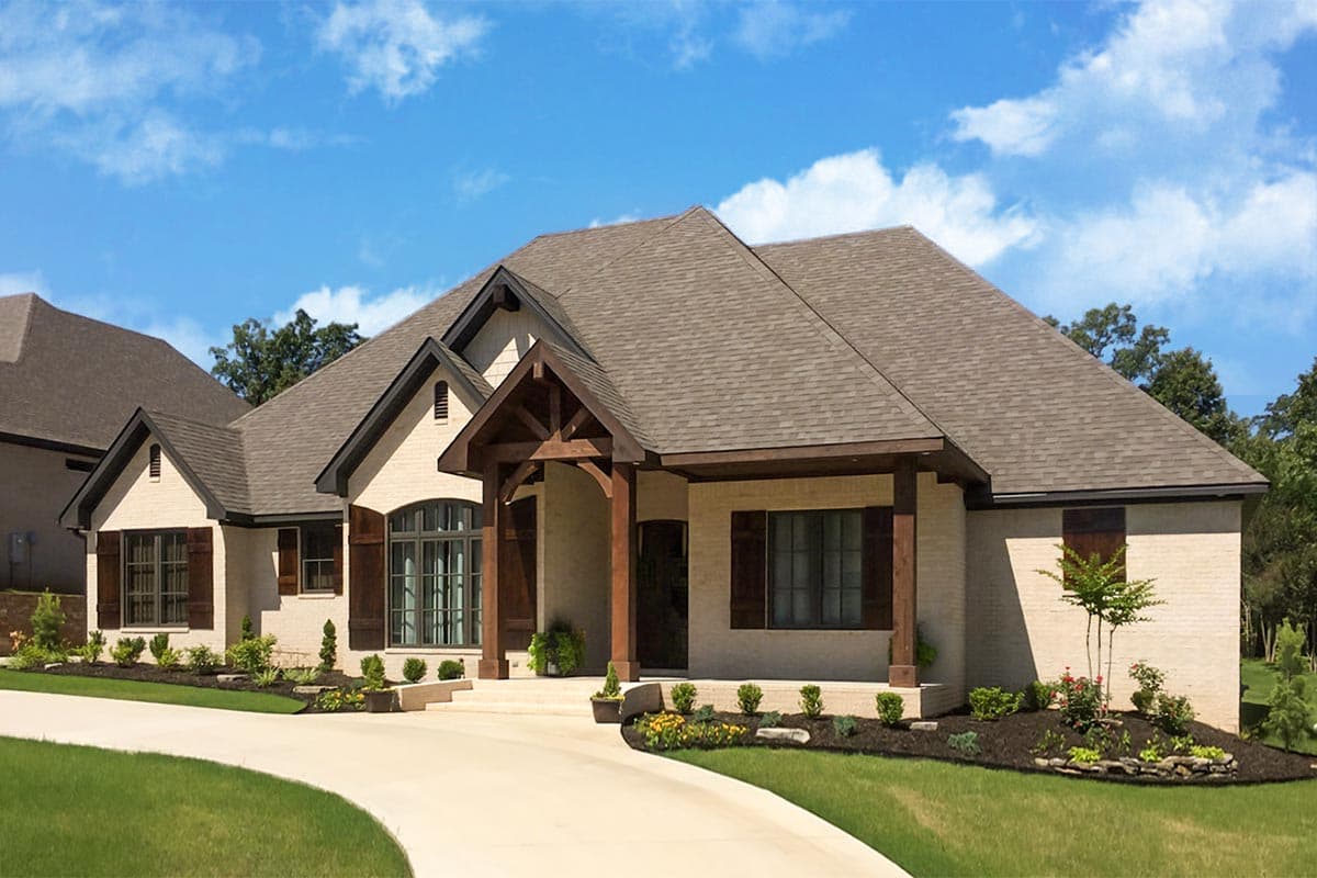 House plan exterior: Ranch-style home with a prominent timber-framed covered entry, multiple gables, and stone accents.
