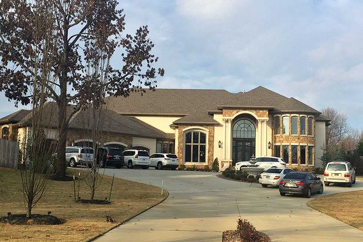 House plan exterior with arched entryway, stone accents, multiple gables, and bay windows.